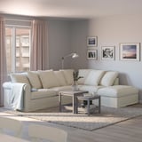 Sala d'estar moderna amb sofà crema, cortines rosa, taula de cafè i paret plena d'art.