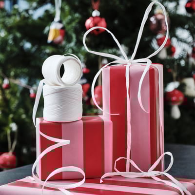 Regals de Nadal: dues caixes embolicades amb paper vermell i cintes blanques, una caixa més gran apilada sobre una de més petita i una bobina de corda blanca a la part superior.