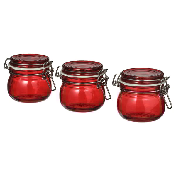 Tres pots de vidre vermell a joc amb pinces metàl·liques i segells de goma alineats en fila.