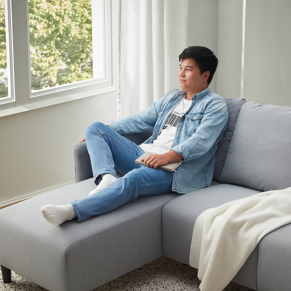 Man in denim relaxes on sofa, gaming.