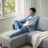 Man in denim relaxes on sofa, gaming.