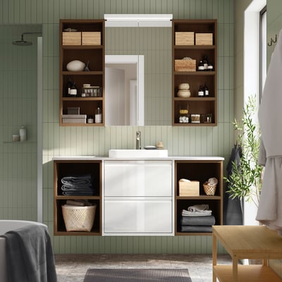 White ÄNGSJÖN bathroom vanity with open/closed storage, sink, toiletries, mirror cabinet, wooden bench, plant, green tiles.