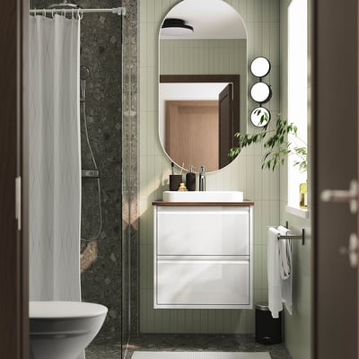 Modern white ÄNGSJÖN bathroom cabinet with glossy finish and green tiles.