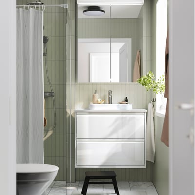 Modern white vanity with sink, mirror cabinet, stool, and striped shower curtain.