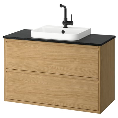 Elegant oak bathroom vanity with black countertop, white sink, and matte black faucet. Wall-mounted with minimalist design, two drawers.