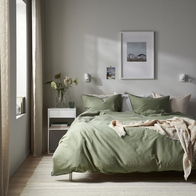 A neatly folded sage green bed linen set, including a duvet cover and pillowcases, made of recycled cotton.