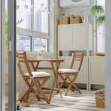 Small wooden ASKHOLMEN dining set with cushions by window, fitting in limited space.