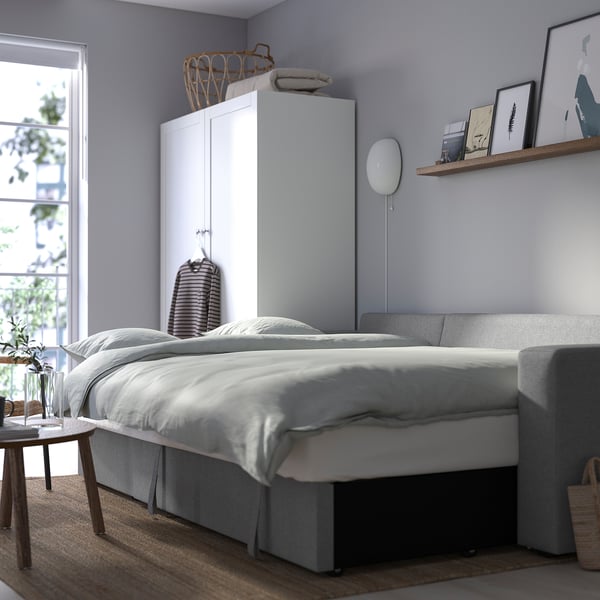 Modern bedroom with BÅRSLÖV sofa-bed, storage, high cabinet, and side table with plant.