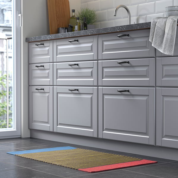 Modern kitchen grey cabinets, marble countertop, and a colourful striped rug in front, providing a vibrant touch to the sleek design.