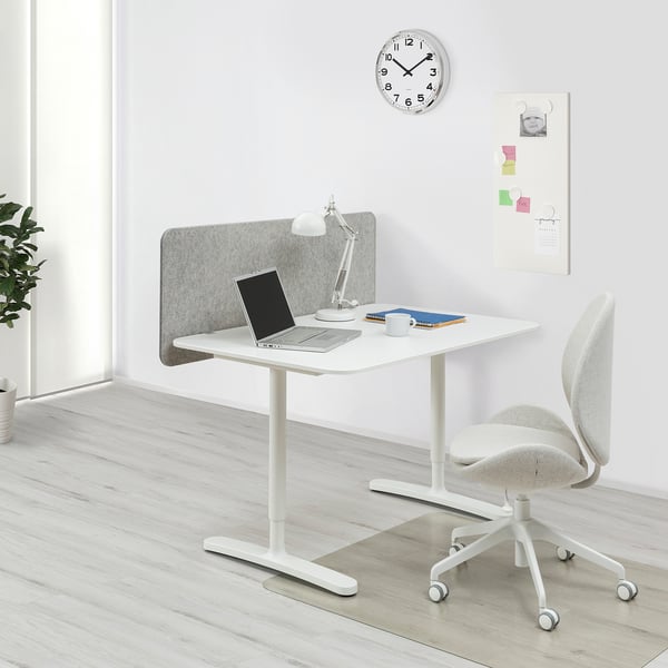 White BEKANT adjustable desk, laptop, lamp, chair, sound-screen, wooden floor, wall clock, pinboard.