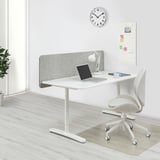 BEKANT white desk with gray screen, laptop, chair, clock, and bulletin board.