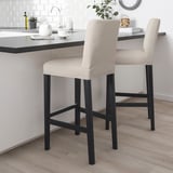 Two beige BERGMUND bar stools with black frames at white kitchen island.