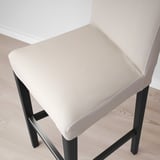 A modern bar stool with a cushioned seat, beige upholstery, and elegant black metal legs. Designed for comfort and style.