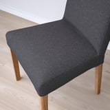 Dark grey upholstered chair with wooden legs on light wooden floor, showcasing quality fabric and craftsmanship.