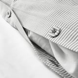 Close-up of striped duvet cover with button, showing soft cotton texture and secure fastening.