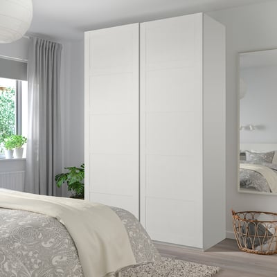 Modern minimalist bedroom with BERGSBO white closet, mirrored closet, bed with gray cover, plants, wicker basket.