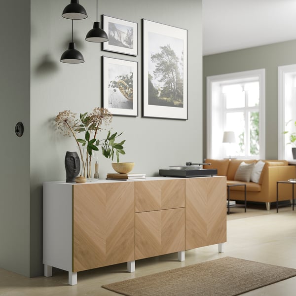 Modern living room with BESTÅ light wood sideboard, black pendants, framed art, and soft-colored furniture.