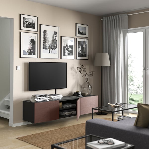 Living room with BESTÅ tv bench in brown. Flat screen tv, books, vase, and curtains. Black & white pictures hang above.