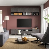 Modern living room with maroon walls, grey furniture: BESTÅ tv bench, sofa, coffee table with books, and floor lamp.