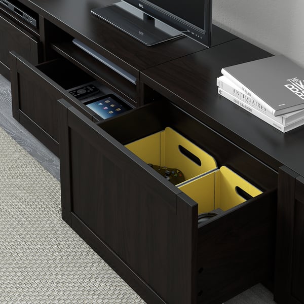 Black tv stand with open drawer revealing yellow game controller.