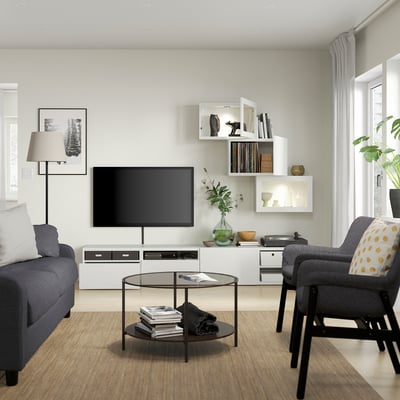 A white BESTÅ tv storage unit. It includes a wide cabinet, two wall cabinets, and shelves. The cabinets are sleek and modern, offering ample storage.
