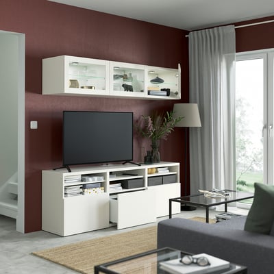 White BESTÅ storage set: three wall cabinets with glass doors and a wide tv bench with adjustable shelves.
