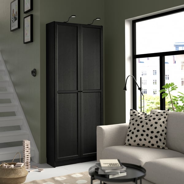 Large black BILLY bookcase; tall, fits under stairs, near window, matches modern room decor.