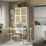 Modern dining area with a white BILLY bookcase with desk, light wood chairs, grey sofa, and kitchen units against a wooden wall.