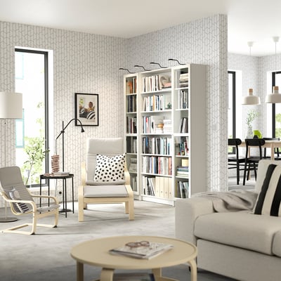 Modern living room with off-white BILLY bookcase, white sofa, and armchairs, wooden coffee table, and large windows.
