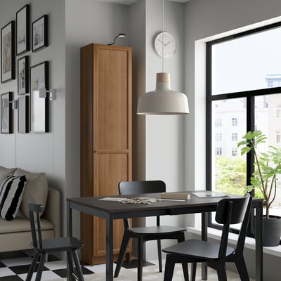 Modern living room with BILLY bookshelf, table, chairs, sofa, lamp, clock, and plant.