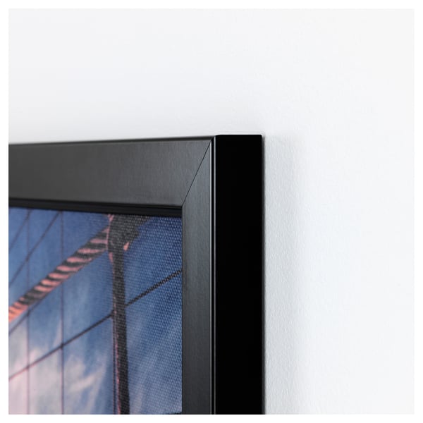 Black-framed artwork mounted on a white wall. The frame is sleek and well-assembled, indicating high quality.