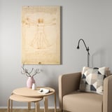 Wooden leonardo da vinci print above beige chair with decor. Minimalist.