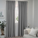 Modern room with BLÅHUVA dark gray curtains, white couch, and potted plant. Curtains are floor-length.
