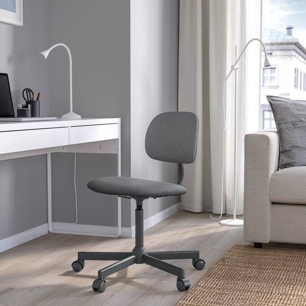 Modern grey office chair near desk, with padded seat & back, fitted under desk.