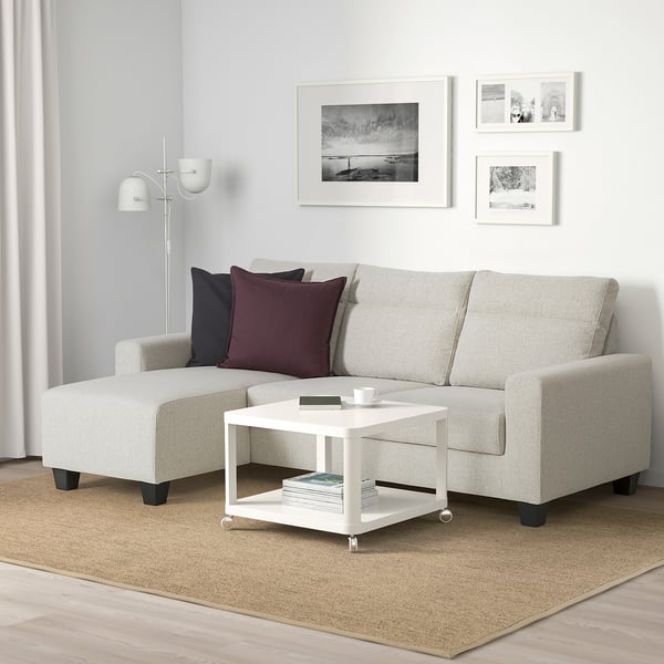 Modern living room with BOLLSTANÄS gray l-shaped sofa, natural rug, white coffee table, and white lamp.