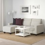 Modern living room with BOLLSTANÄS gray l-shaped sofa, natural rug, white coffee table, and white lamp.