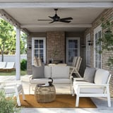 Modern outdoor lounge with BONDHOLMEN 2-seat sofa, jute rug, and wicker coffee table with plant.