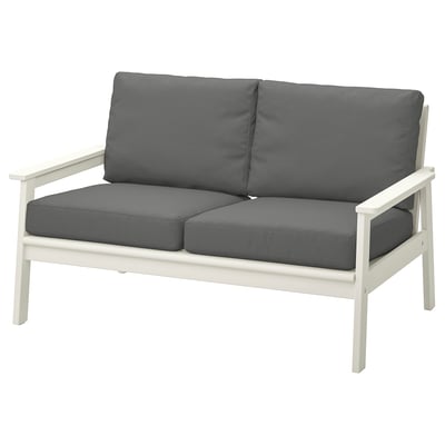 Modern white outdoor loveseat with dark gray cushions, sleek design, acacia wood frame.