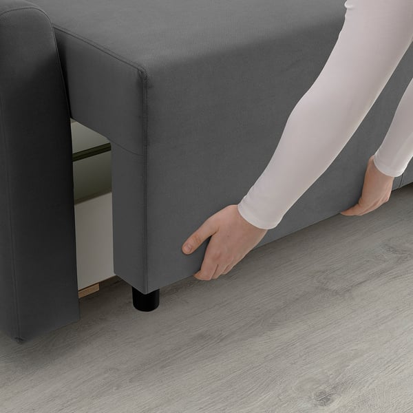 A person transforming a sofa into a bed by pulling out a section, showcasing its storage function.