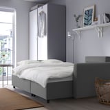 Modern compact living space with gray sofa bed, built-in storage, decor, and large window.