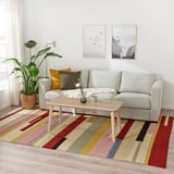 Living room with light gray sofa, wooden coffee table, colorful striped rug, and potted plant. Two framed pictures hang above the sofa.
