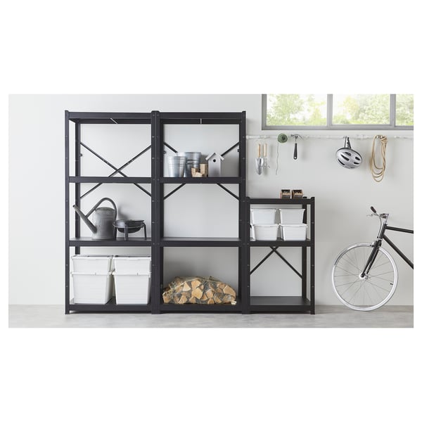 Black metal shelves with compartments, holding buckets, tools, and logs. Bike leans against wall.