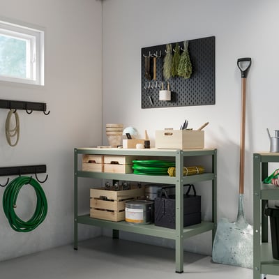 Green BROR shelf with tools and boxes; black pegboard with hanging tools; small left window.