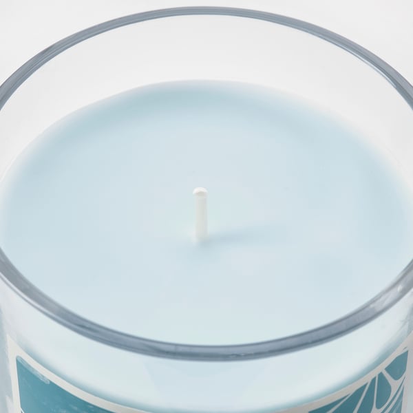 Circular glass candle with blue-tinted wax, central wick, polished edge.