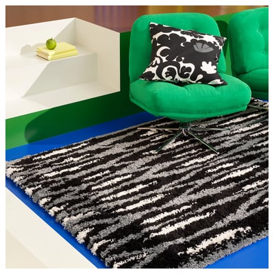 Black and white striped rectangular rug with a shaggy texture. Part of the nytillverkad collection, it a modern design with diagonal patterns.