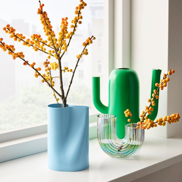 Blue, green, & clear vases: one large blue with branches & berries, plus a cactus & clear curved vase.