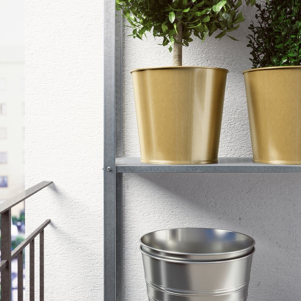 Gold-colored metal plant pots on shelves with green plants, enhancing home decor.