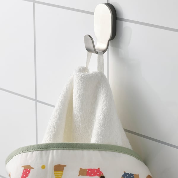 A white towel with colorful dog prints hangs on a hook. A green stripe borders the bottom.
