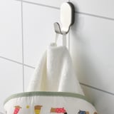 A white towel with colorful dog prints hangs on a hook. A green stripe borders the bottom.