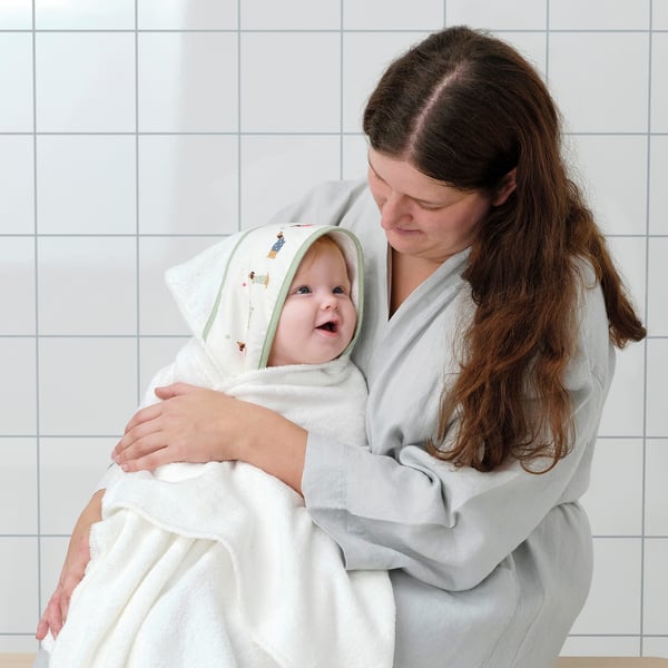 Mother holding wrapped baby in cozy towel with hood.